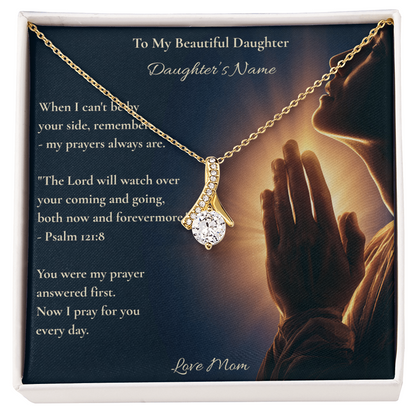 Hand holding a daughter message card and necklace with Psalm 121:8 outdoors on grass