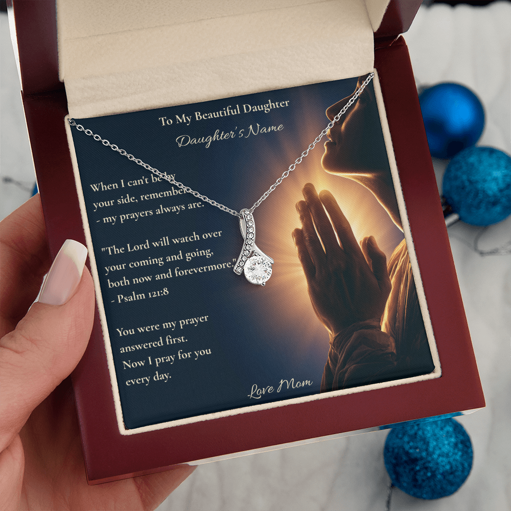 Hand holding a daughter necklace card with Psalm 121:8 beside blue ornaments